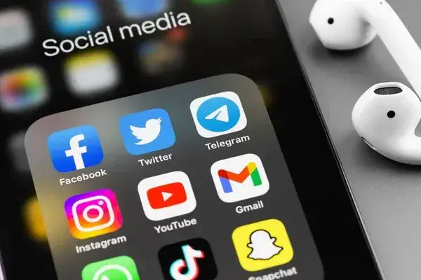 osoba używająca smartfona do przeglądania medi&oacute;w społecznościowych z ikonami Facebook, Instagram, TikTok