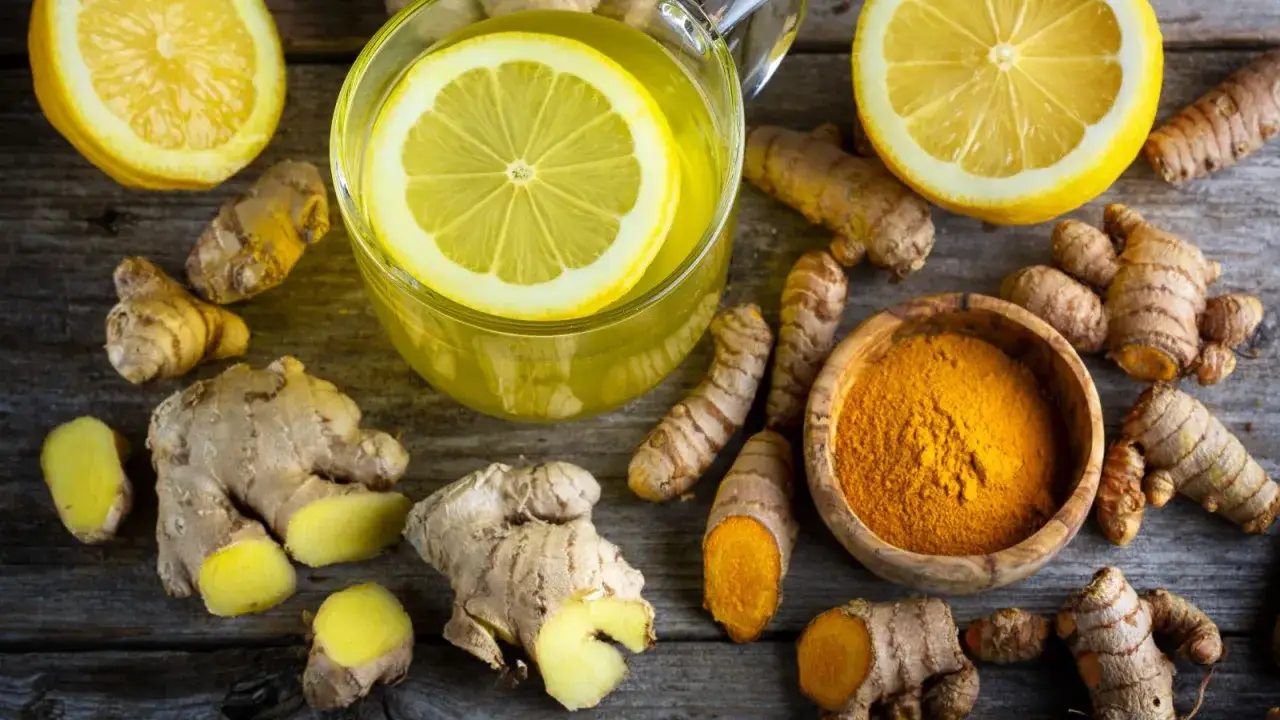 Napój z cytryną i imbirem, obok świeżych korzeni i kurkumy w proszku. Zastanawiasz się, ile imbiru dziennie?