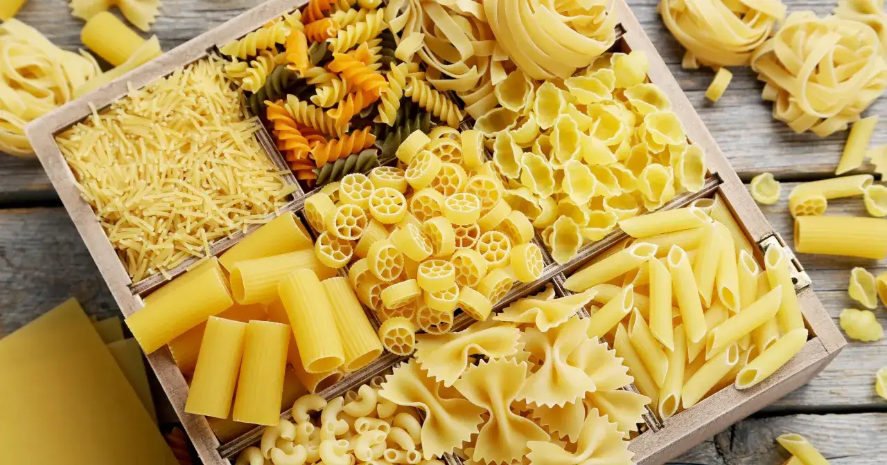 Różnorodne makarony w drewnianej skrzynce: świderki, kokardki, rurki, muszelki. Idealne, by czym zastąpić makaron pszenny.