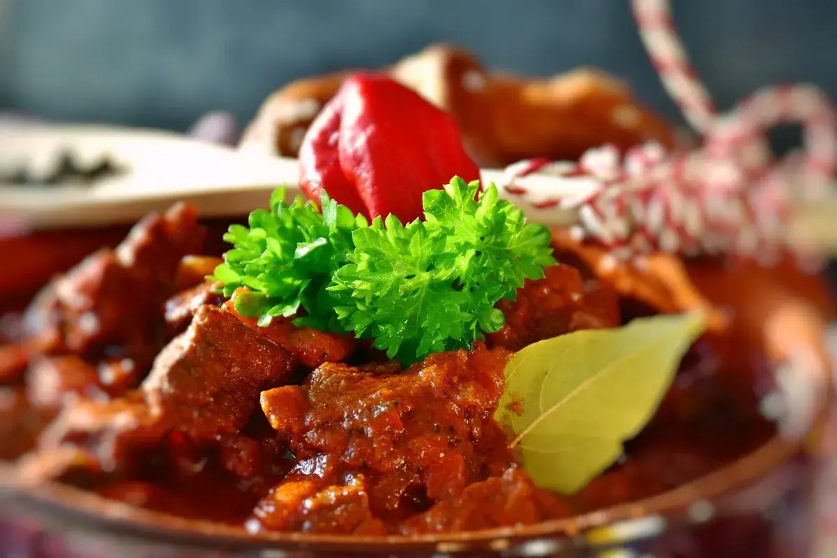 Gęsty, aromatyczny sos pieczeniowy z kawałkami mięsa, ozdobiony natką pietruszki, czerwoną papryczką i liściem laurowym.