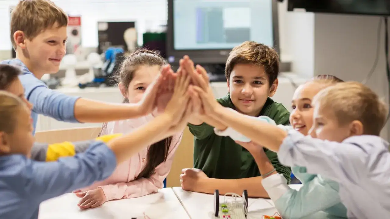 Uśmiechnięte dzieci wsp&oacute;łpracujące przy projekcie w klasie