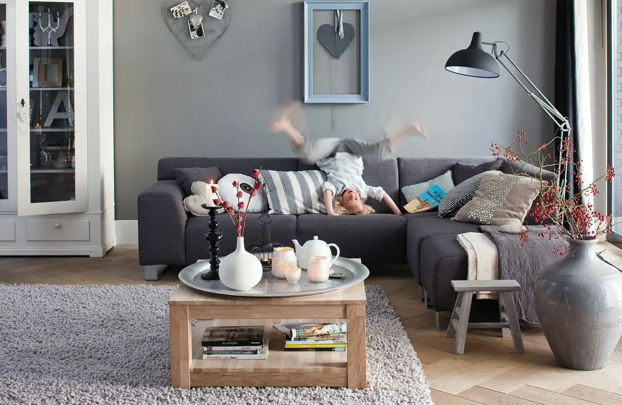 Dziecko robi fikołka na kanapie w przytulnym salonie w stylu holenderskim.