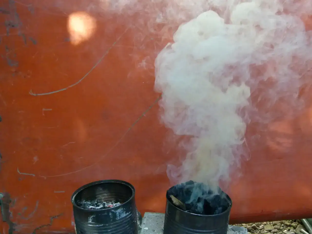 Dwa metalowe pojemniki z żarzącym się węglem, z których unosi się biały dym. Co oznacza żółty dym z komina? To pytanie może być związane z tym, co się pali.