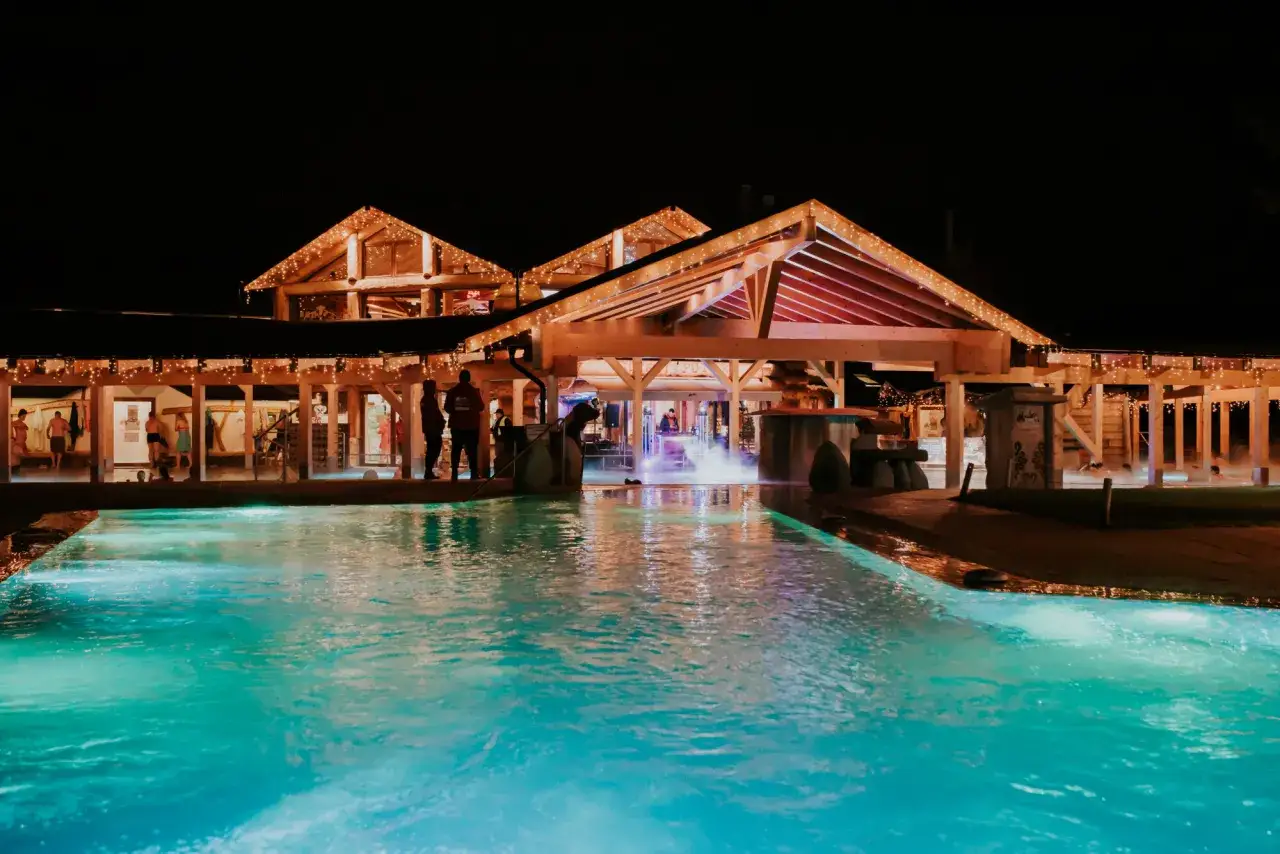 Nocny basen z podświetlaną wodą i drewnianą architekturą, tworzący magiczną atmosferę. Idealne miejsce na relaks w day spa Zakopane.