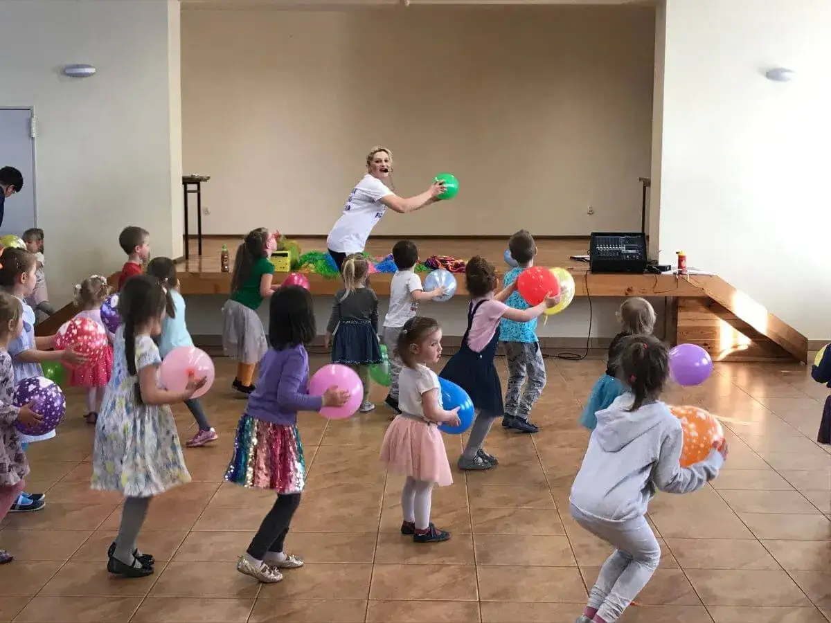 Radosne zabawy taneczne dla dzieci z balonami. Dzieci tańczą i bawią się kolorowymi balonami pod okiem animatorki.