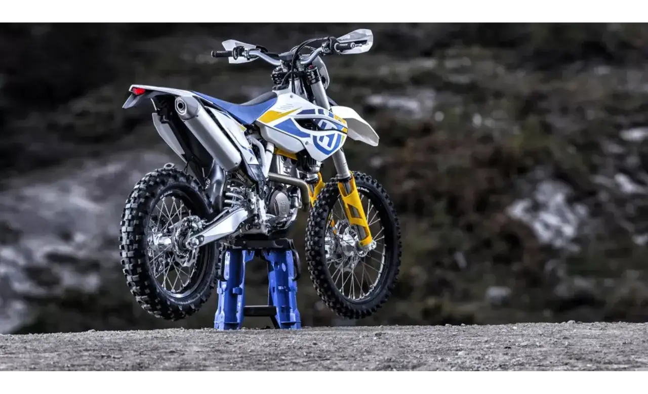 Husqvarna 250 FE gotowy na teren. Biało-niebieski motocykl z ż&oacute;łtymi akcentami na amortyzatorach.