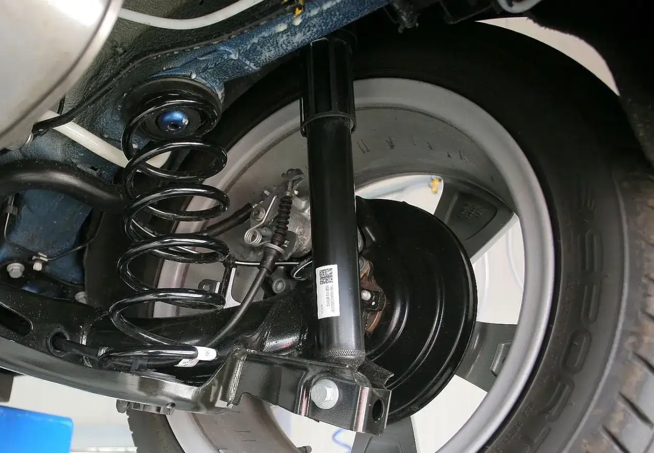 Widok z dołu na tył samochodu, widoczna sprężyna i amortyzator. Wymiana amortyzatorów tył zakończona sukcesem.
