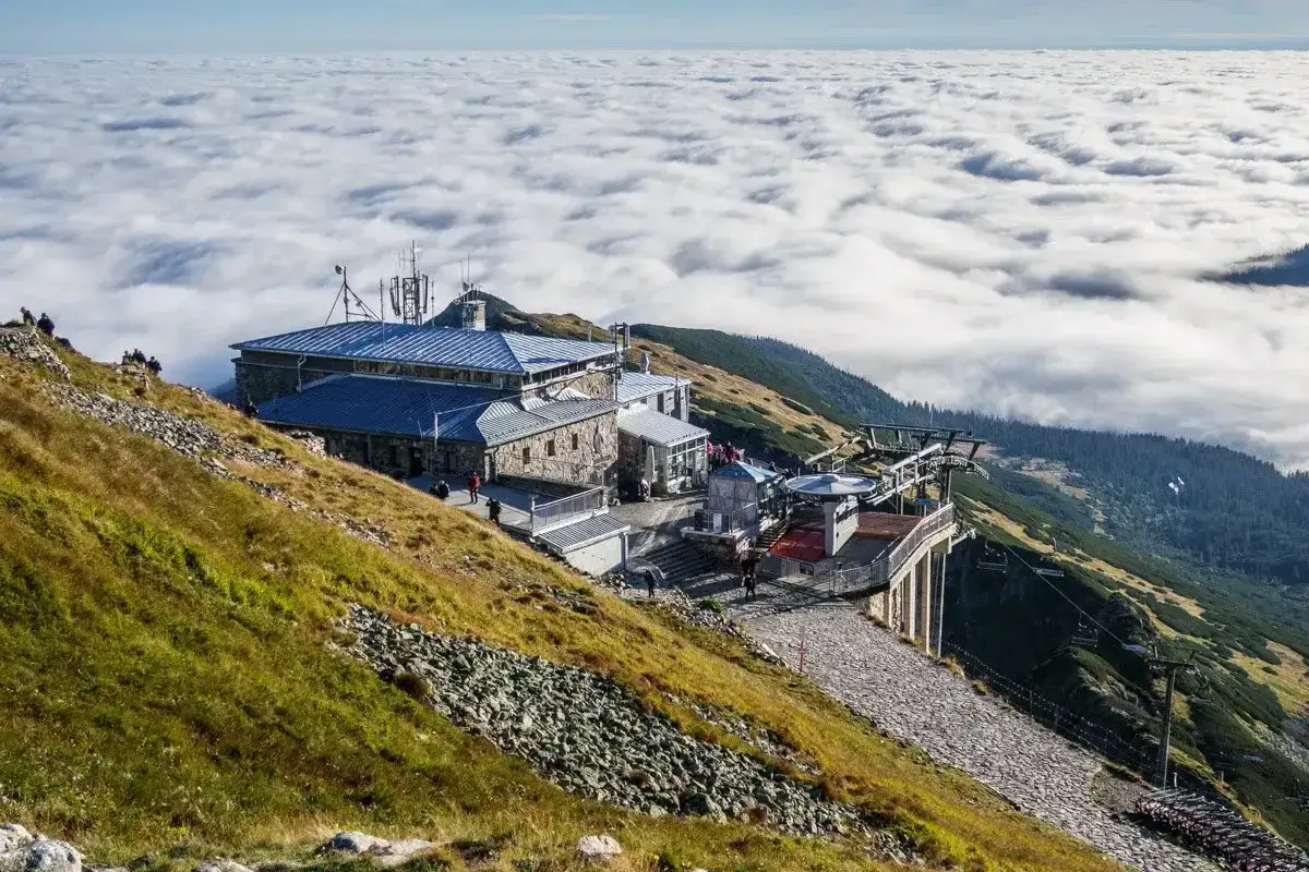 Widok na górną stację kolejki na Kasprowy Wierch, otoczoną morzem chmur. Szlaki na Kasprowy Wierch prowadzą przez malownicze, skaliste zbocza.