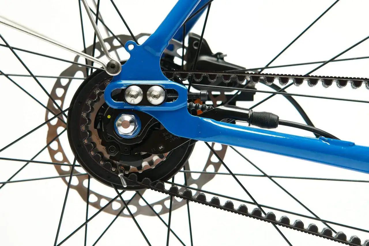 Niebieski rower z napędem na pasek. Widoczna tylna przerzutka, zębatka i hamulec tarczowy.