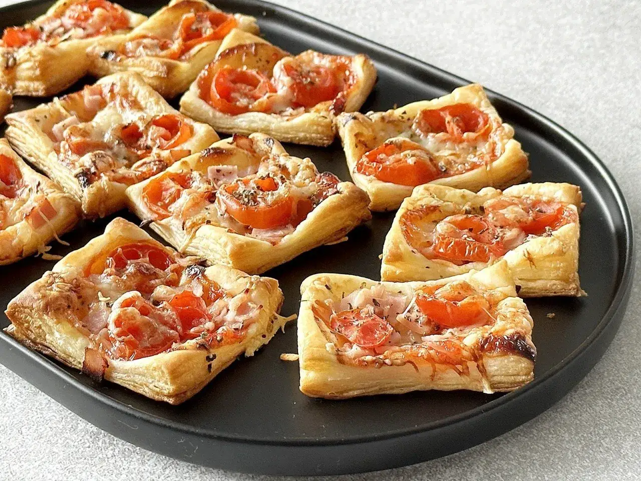 Pizzerinki z ciasta francuskiego z pomidorkami i serem, idealne na szybką przekąskę.