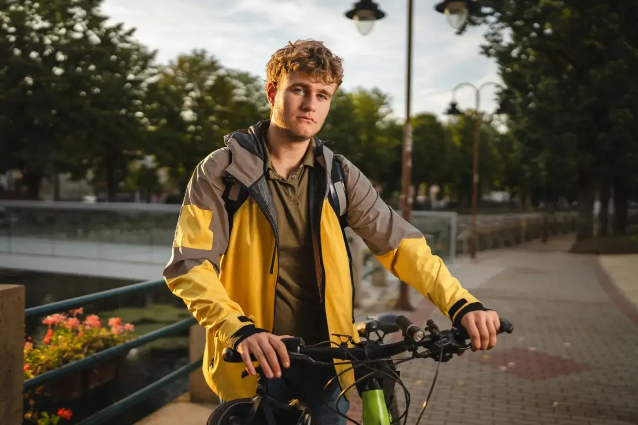 Młody mężczyzna w żółtej kurtce, gotowy do pracy jako kurier Glovo. Dowiedz się, jak zostać kurierem Glovo i zacznij zarabiać!