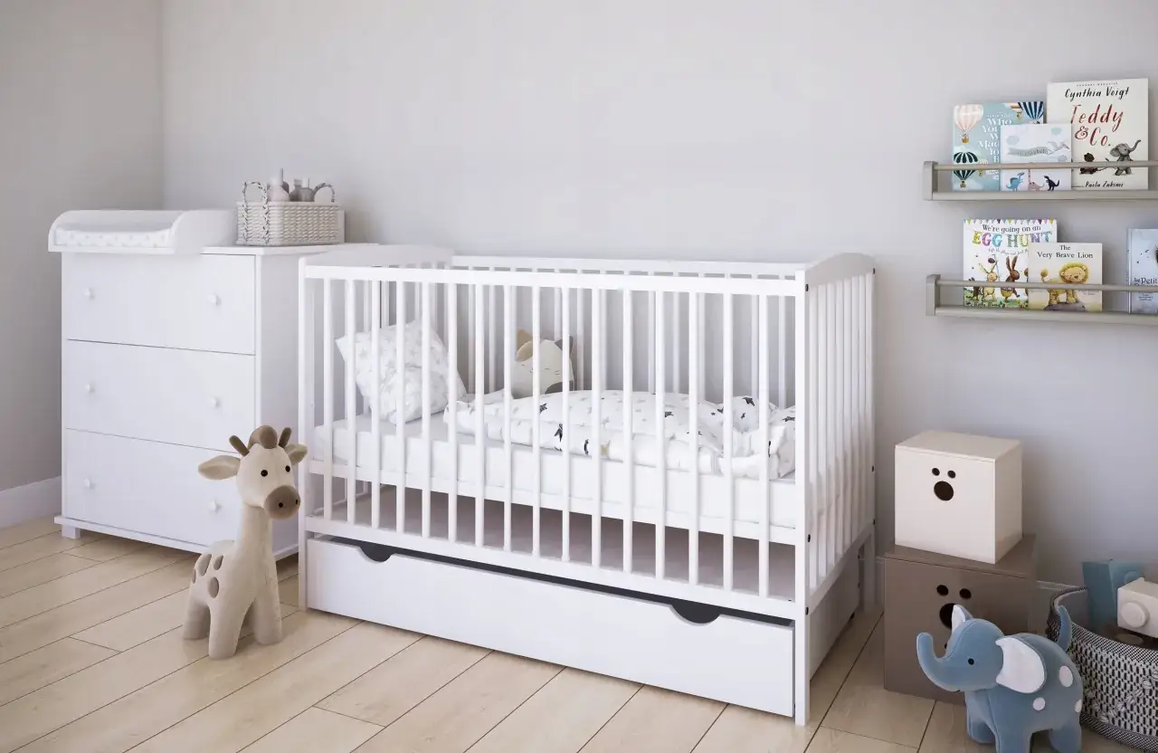 Białe ł&oacute;żeczko dla dziecka z szufladą, komoda z przewijakiem i pluszowa żyrafa. Idealne miejsce na pierwsze drzemki. Kiedy kupić ł&oacute;żeczko dla dziecka? Już teraz!
