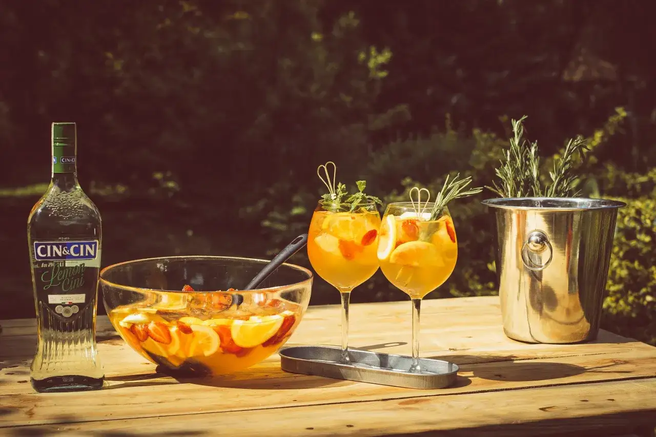 Czy warto kupować drogie giny do drinków mieszanych z owocami? Dwa drinki z owocami i miska ponczu na stole.