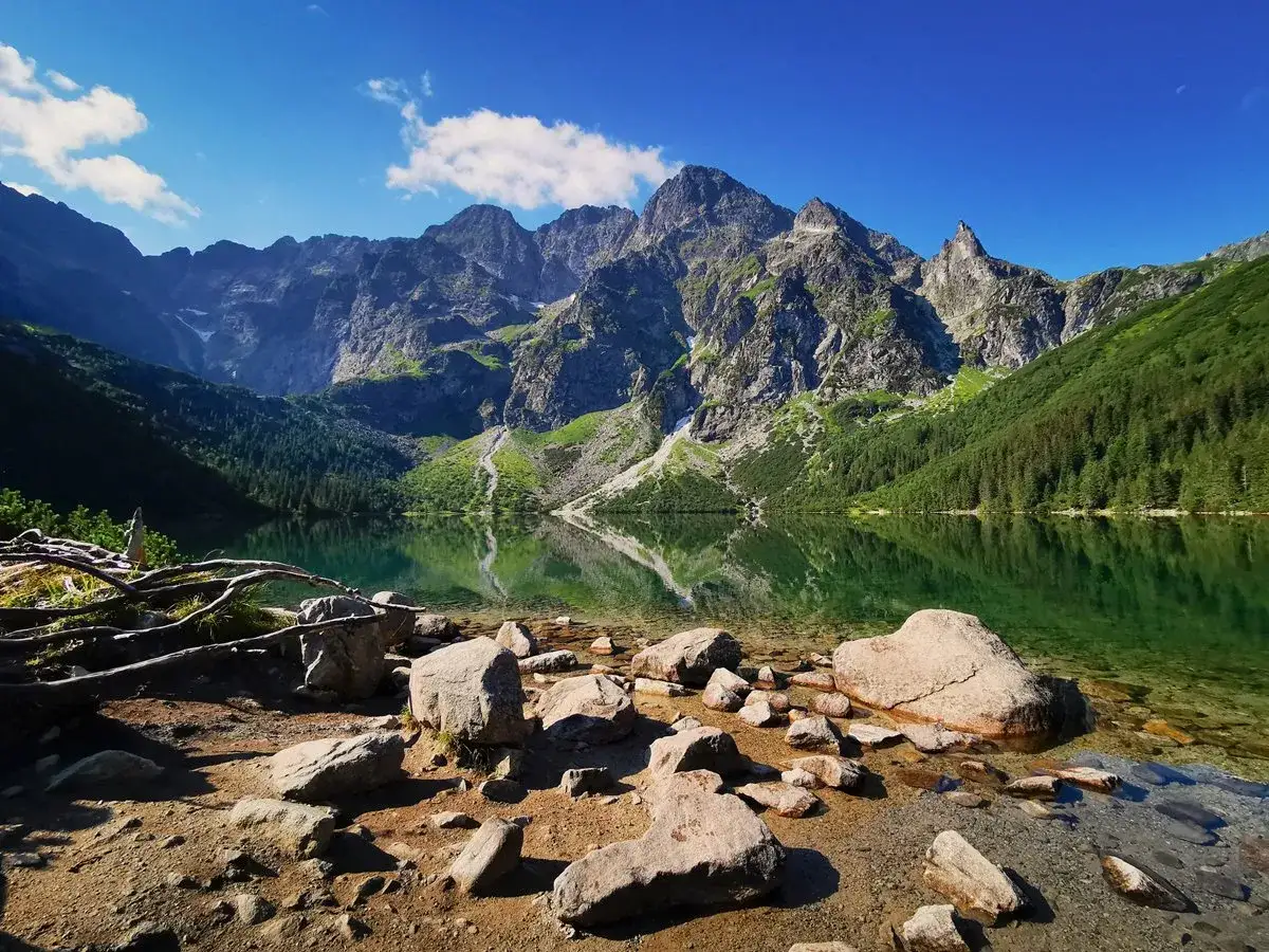Kamienista plaża nad Morskim Okiem, odbijającym majestatyczną korona Tatr Polskich.