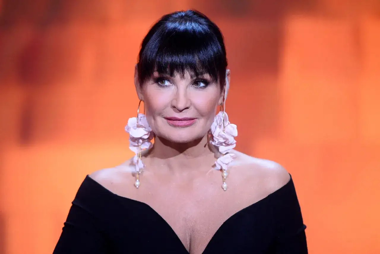 Iwona Pawłowicz, znana z wyrazistego stylu, prezentuje się w czarnej sukni z odkrytymi ramionami i efektownymi kolczykami.