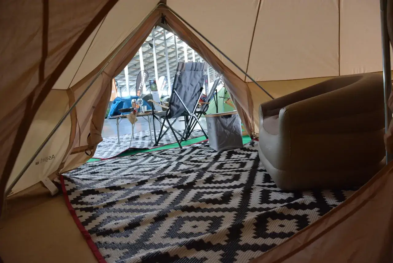 Wnętrze namiotu z materacem, krzesłem i dywanem. Pomaga to zdecydować, jaki namiot wybrać na kemping.