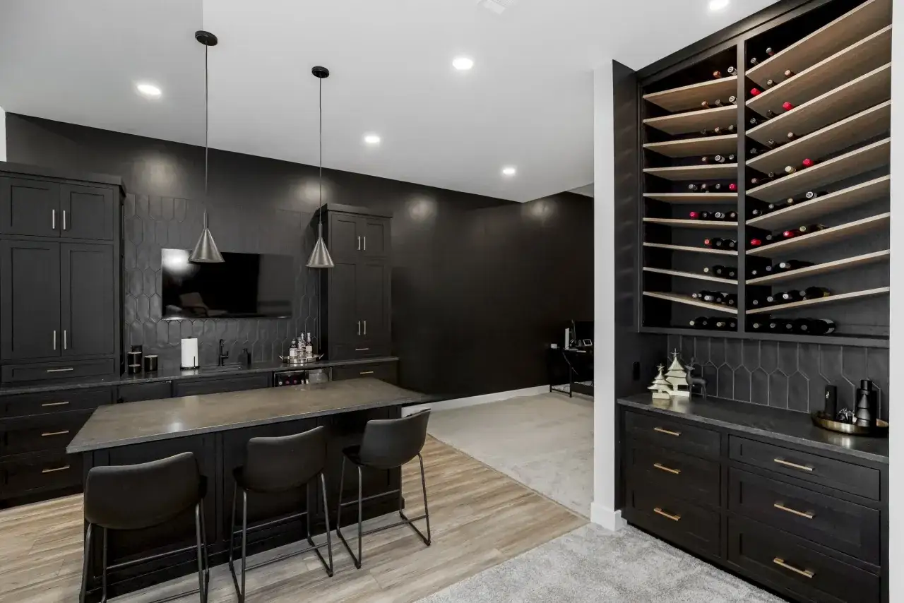 Nowoczesna piwnica z czarnymi meblami, wyspą barową i regałem na wino. Inspiracje dla miłośników wina.