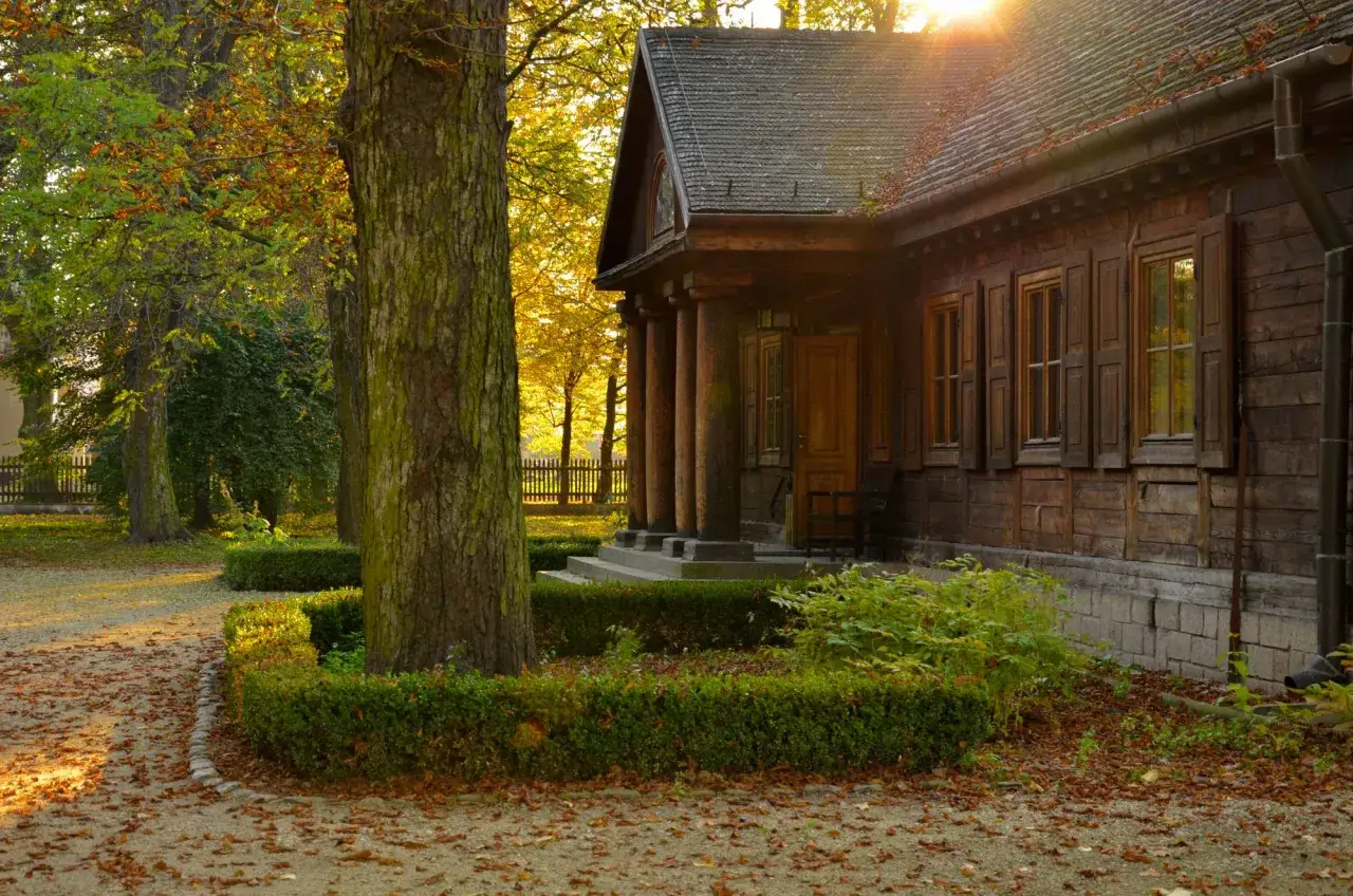 Jesienne słońce oświetla drewniany dom z werandą, przypominający, gdzie jest młyn z filmu 