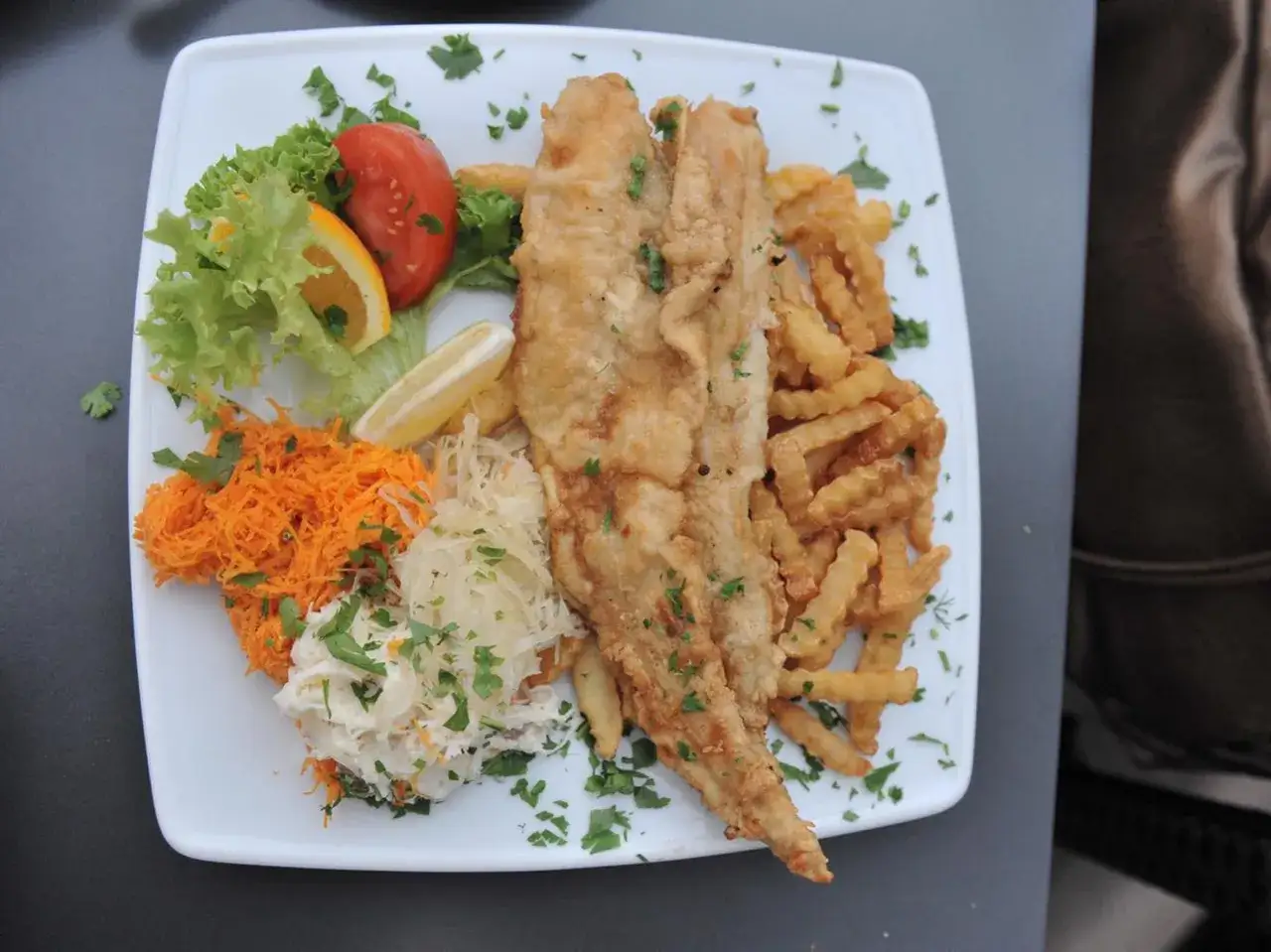 Smażona ryba z frytkami, surówką i ćwiartką cytryny. Zastanawiasz się, ile kosztuje obiad nad morzem?