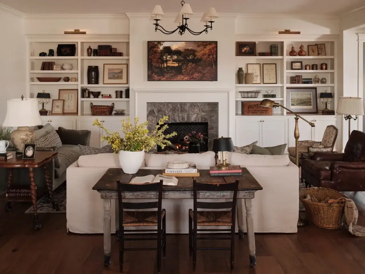 Przytulny salon w stylu kolonialnym z kominkiem, regałami pełnymi książek i bibelot&oacute;w, wygodną kanapą i stylowymi meblami.