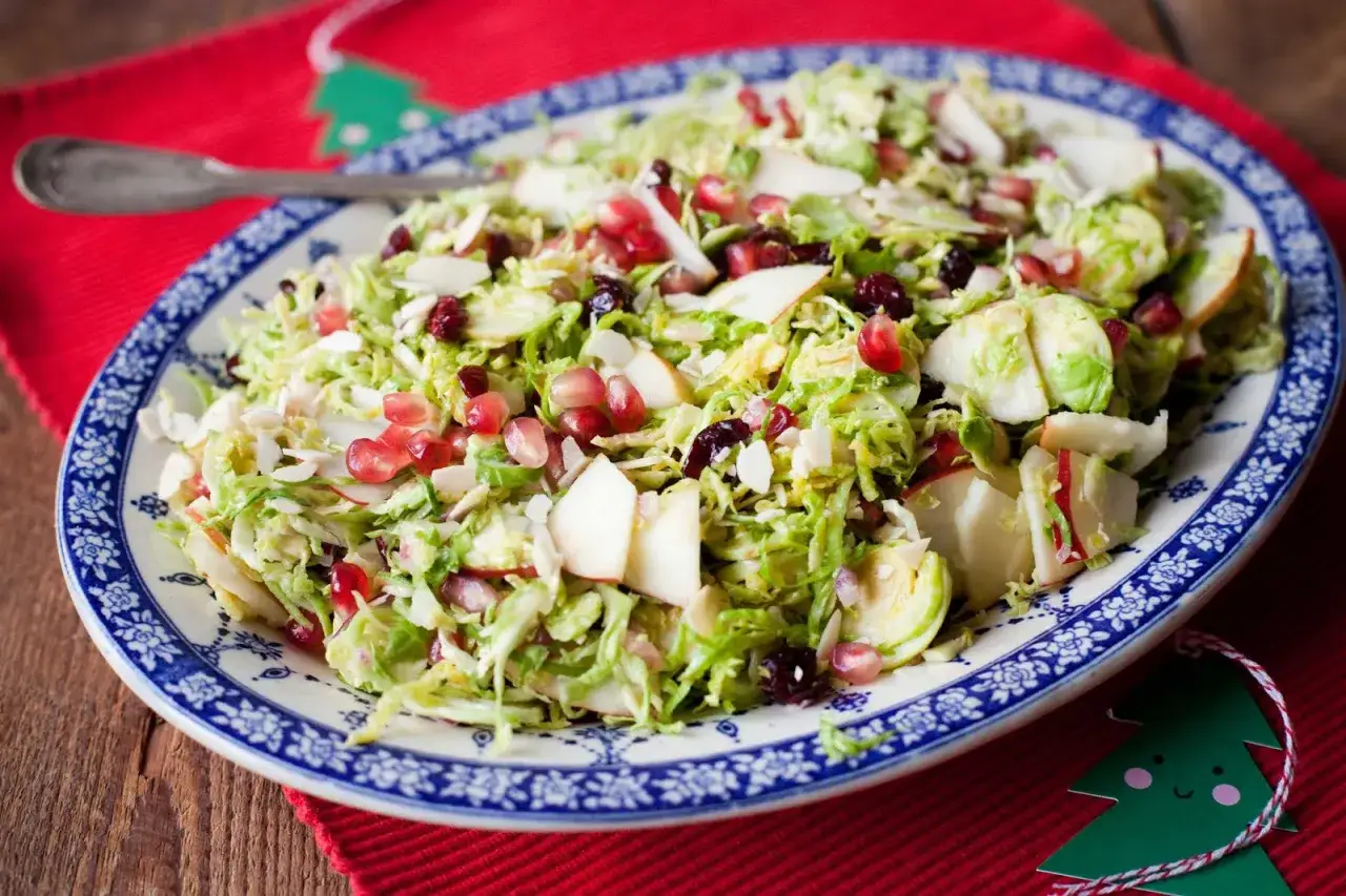Pyszna sałatka z brukselki z jabłkiem, żurawiną i migdałami na świątecznym talerzu.