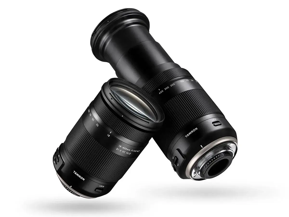Dwa obiektywy Tamron 18-400 mm, jeden z wysuniętym zoomem, drugi z zasuniętym, leżą obok siebie.