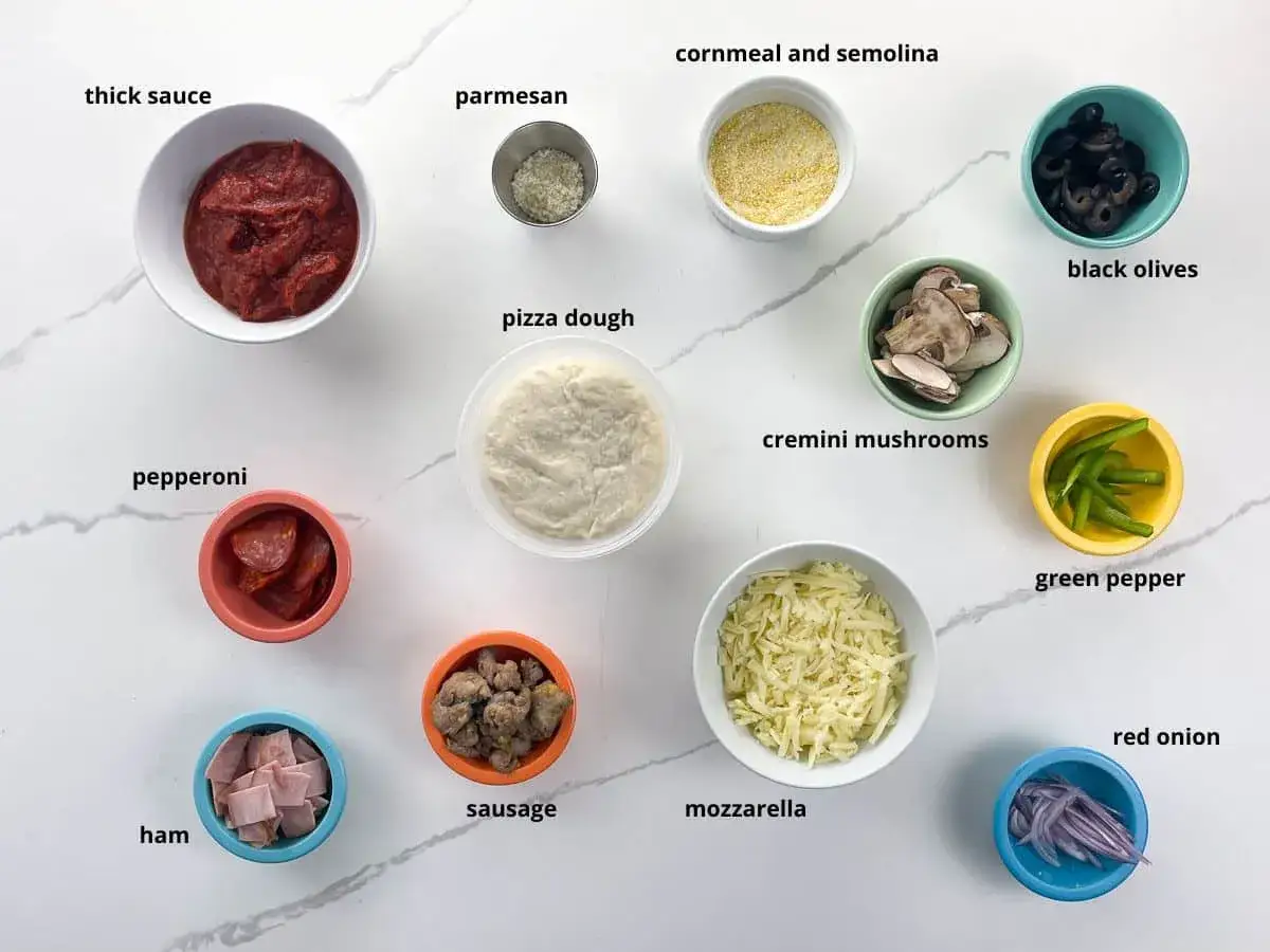 Wszystkie potrzebne dodatki do pizzy: sos, ser, pepperoni, szynka, kiełbaska, pieczarki, oliwki, papryka, cebula, mąka kukurydziana i semolina.