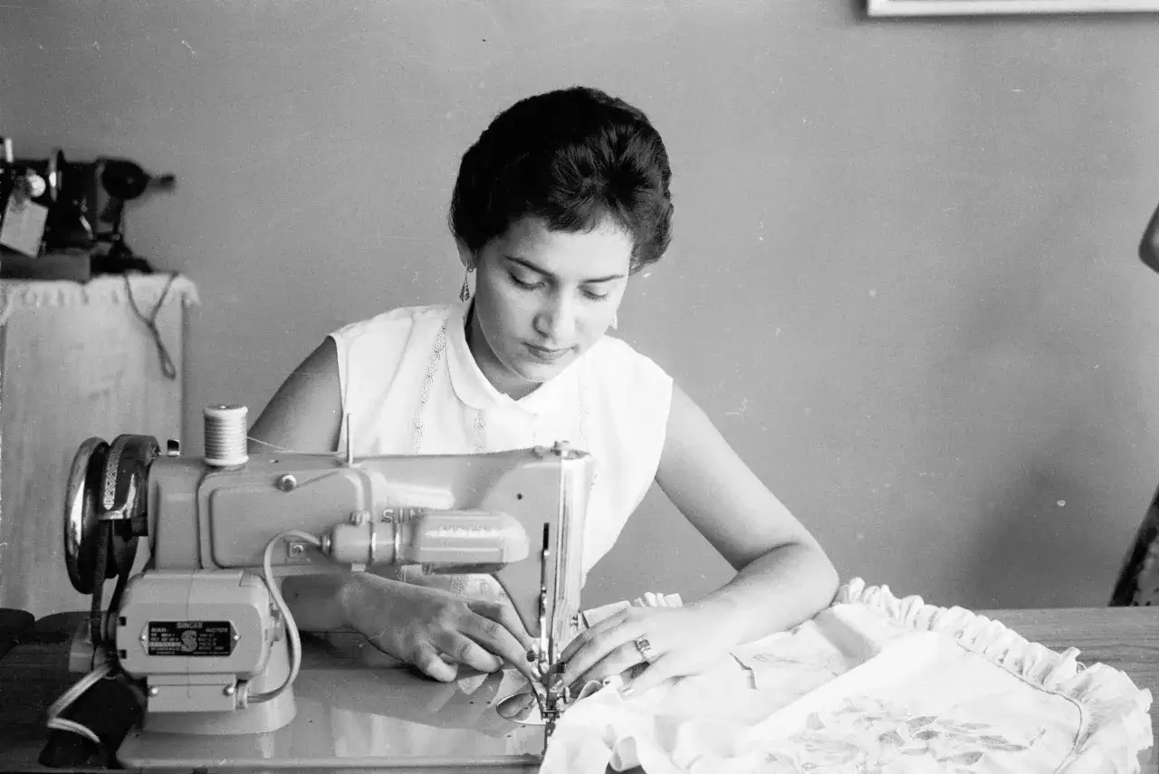 Kobieta uczy się, jak przerobić bluzkę, pracując przy maszynie do szycia.