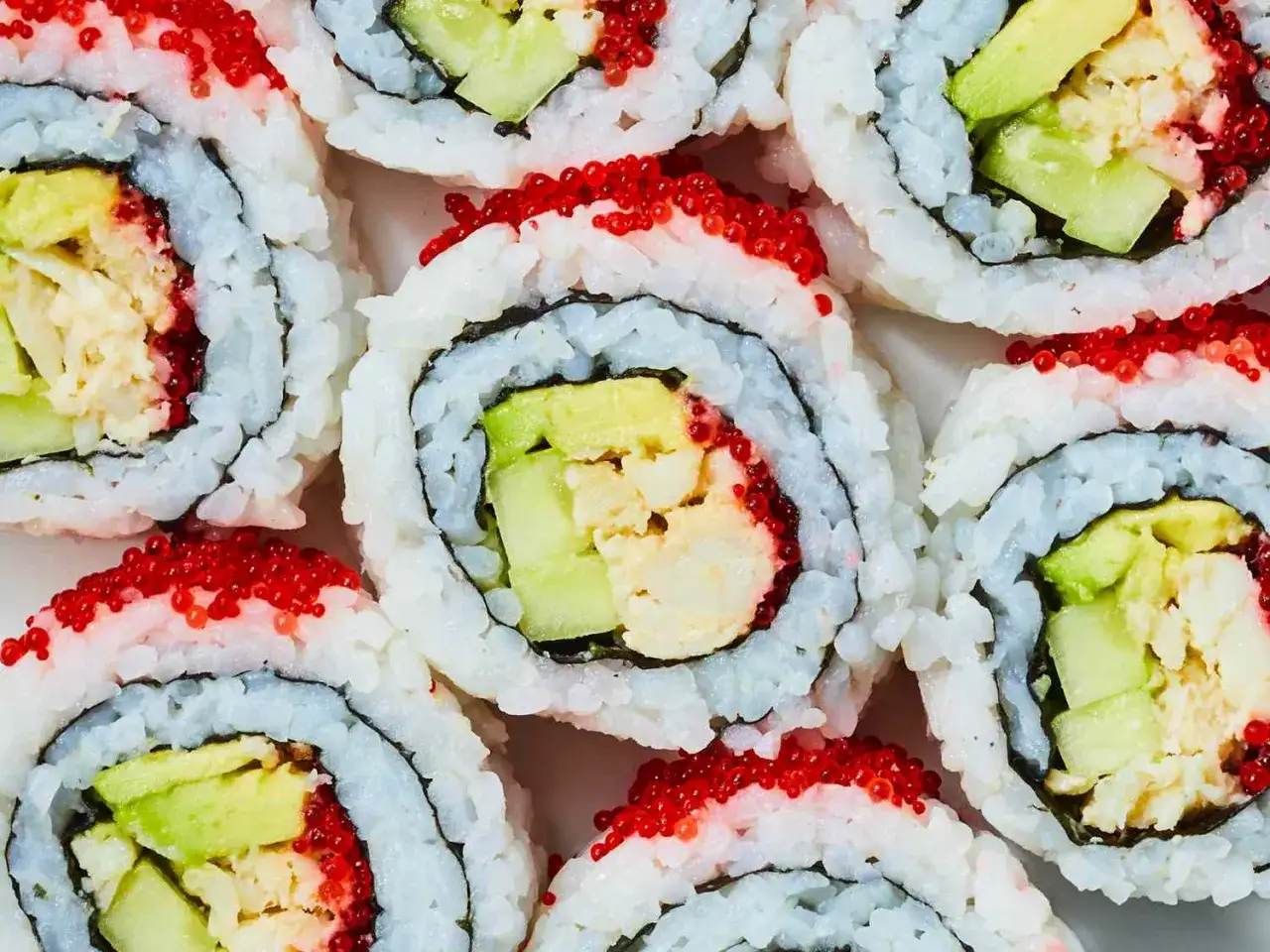 California roll sushi z awokado, ogórkiem i krewetkami, posypane czerwonym ikrą.