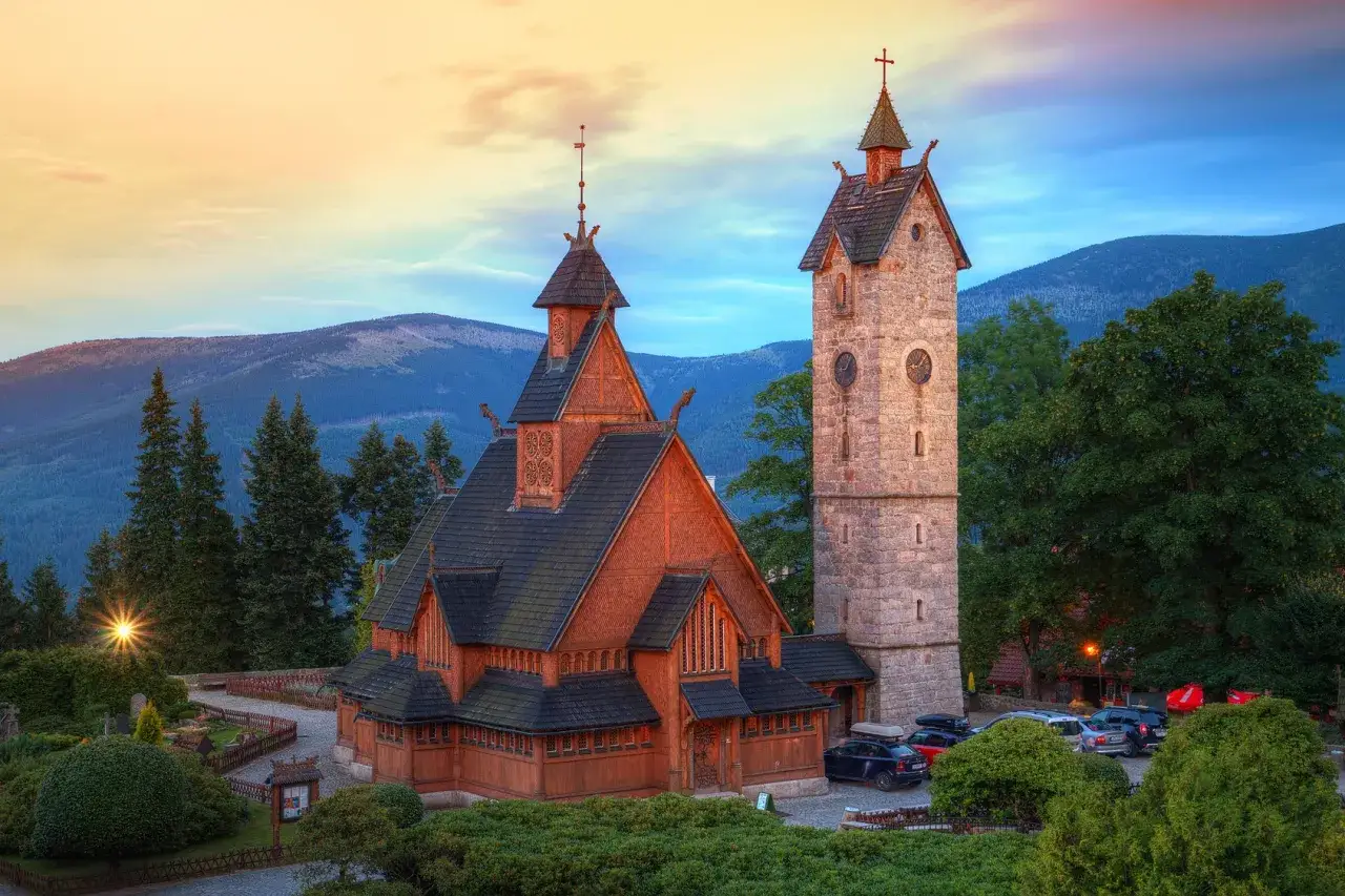 Drewniany kościółek i kamienna wieża z zegarem w Karkonoszach. Idealne miejsce na spokojny weekend w Karpaczu.