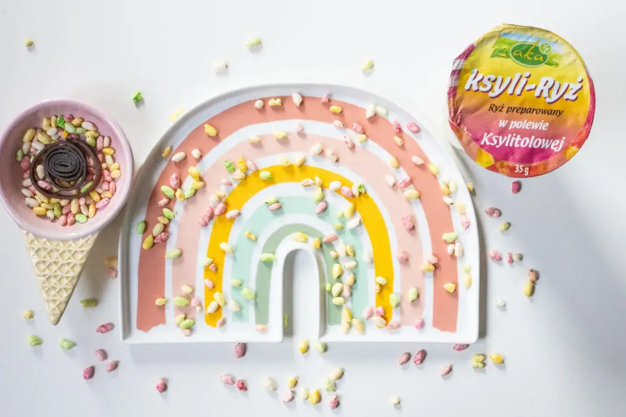 Kolorowe chrupki ryżowe na talerzyku w kształcie tęczy i w rożku. Idealne słodycze dla 2 latka, kt&oacute;re wyglądają jak małe kamyczki.