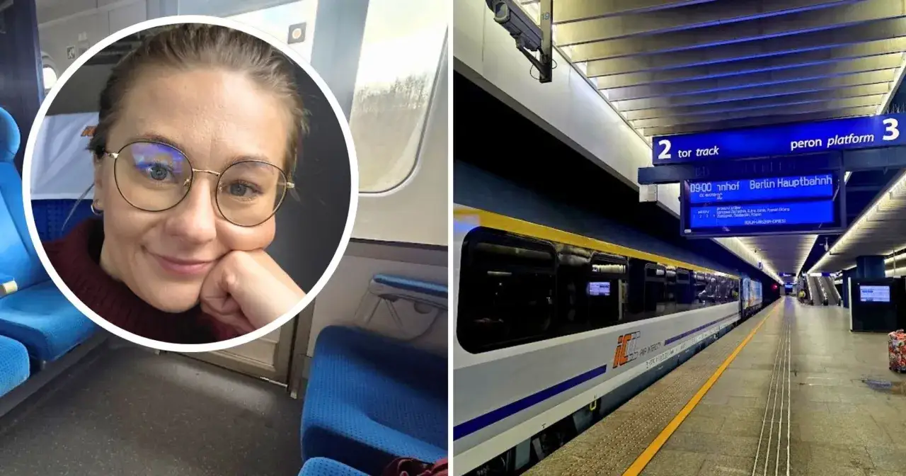 Uśmiechnięta kobieta w okularach w pociągu, obok tablica informacyjna z napisem 