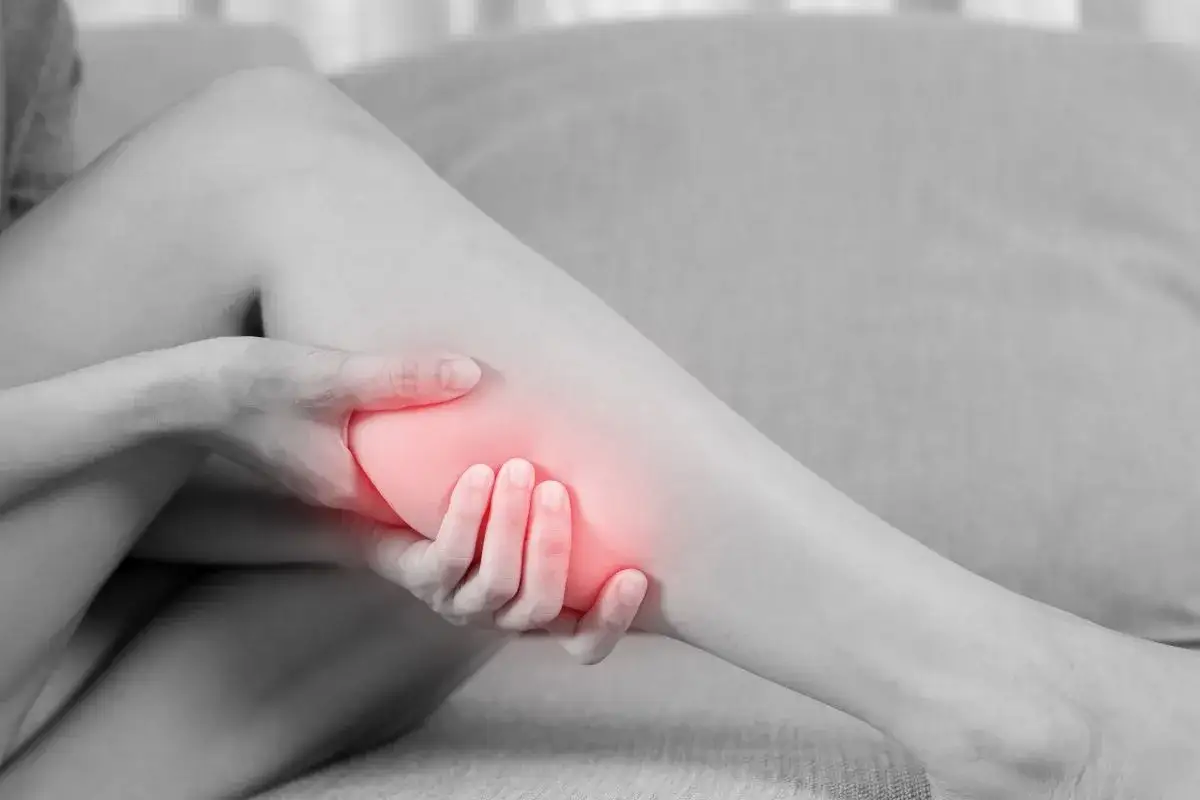 Kobieta masuje bolącą łydkę, szukając domowych sposobów na ból łydek.