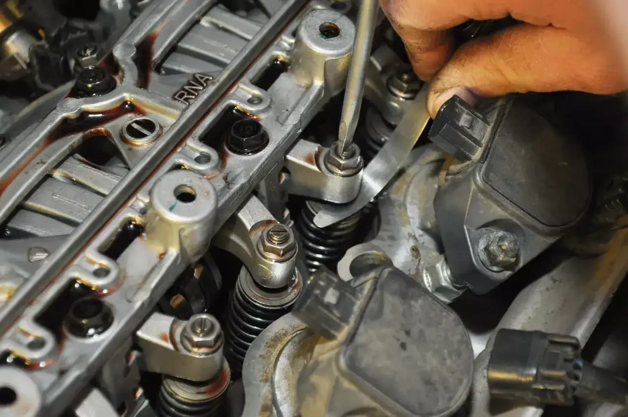 Mechanik precyzyjnie ustawia zawory silnika, używając śrubokręta i szczelinomierza.