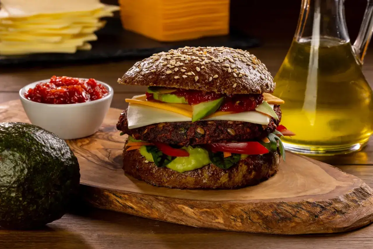 Pyszny burger z buraka z awokado, serem i sosem na drewnianej desce.