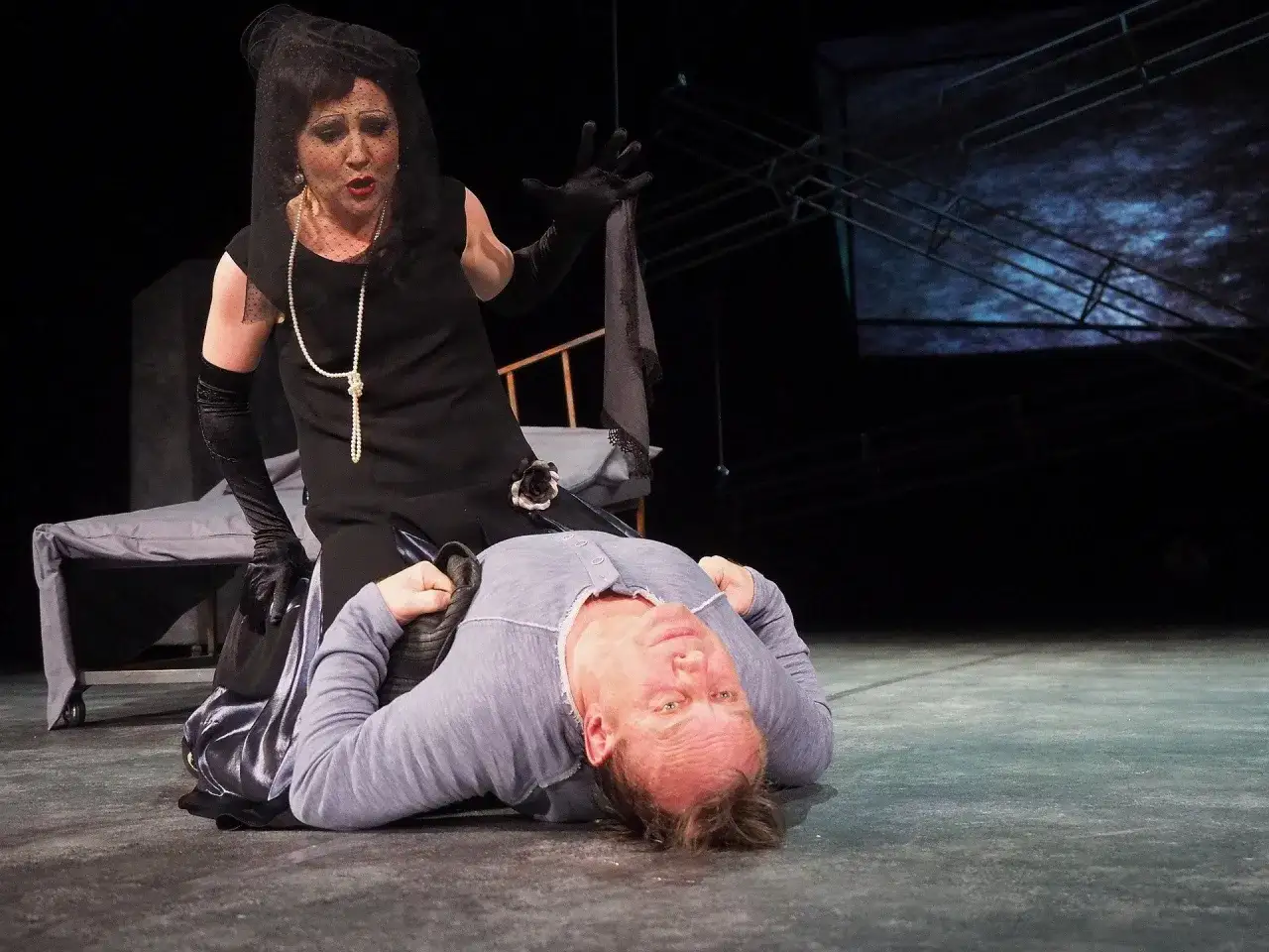 Aktorka w żałobnej kreacji klęczy nad leżącym mężczyzną. Czy to finałowa scena? Ile trwa spektakl w teatrze?