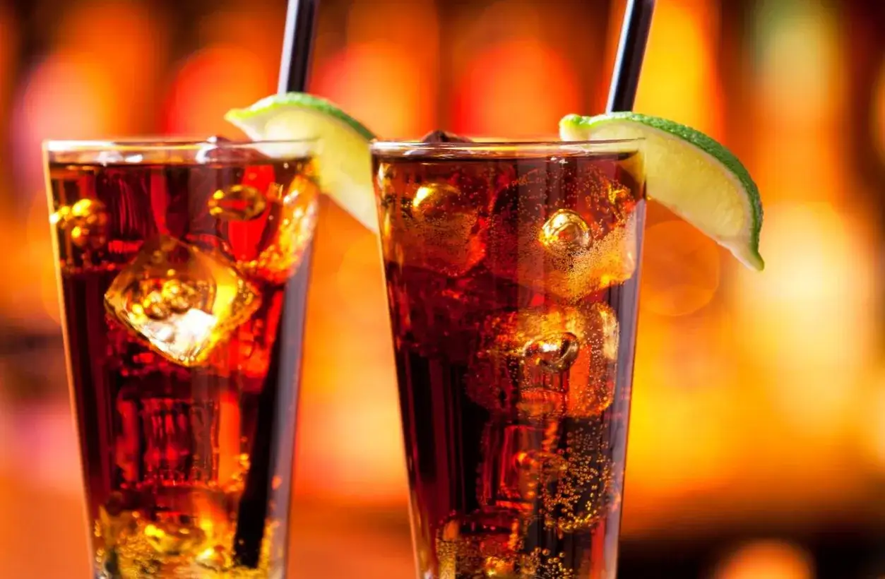 Dwa orzeźwiające drinki Long Island Iced Tea z lodem i plasterkiem limonki, gotowe do podania.