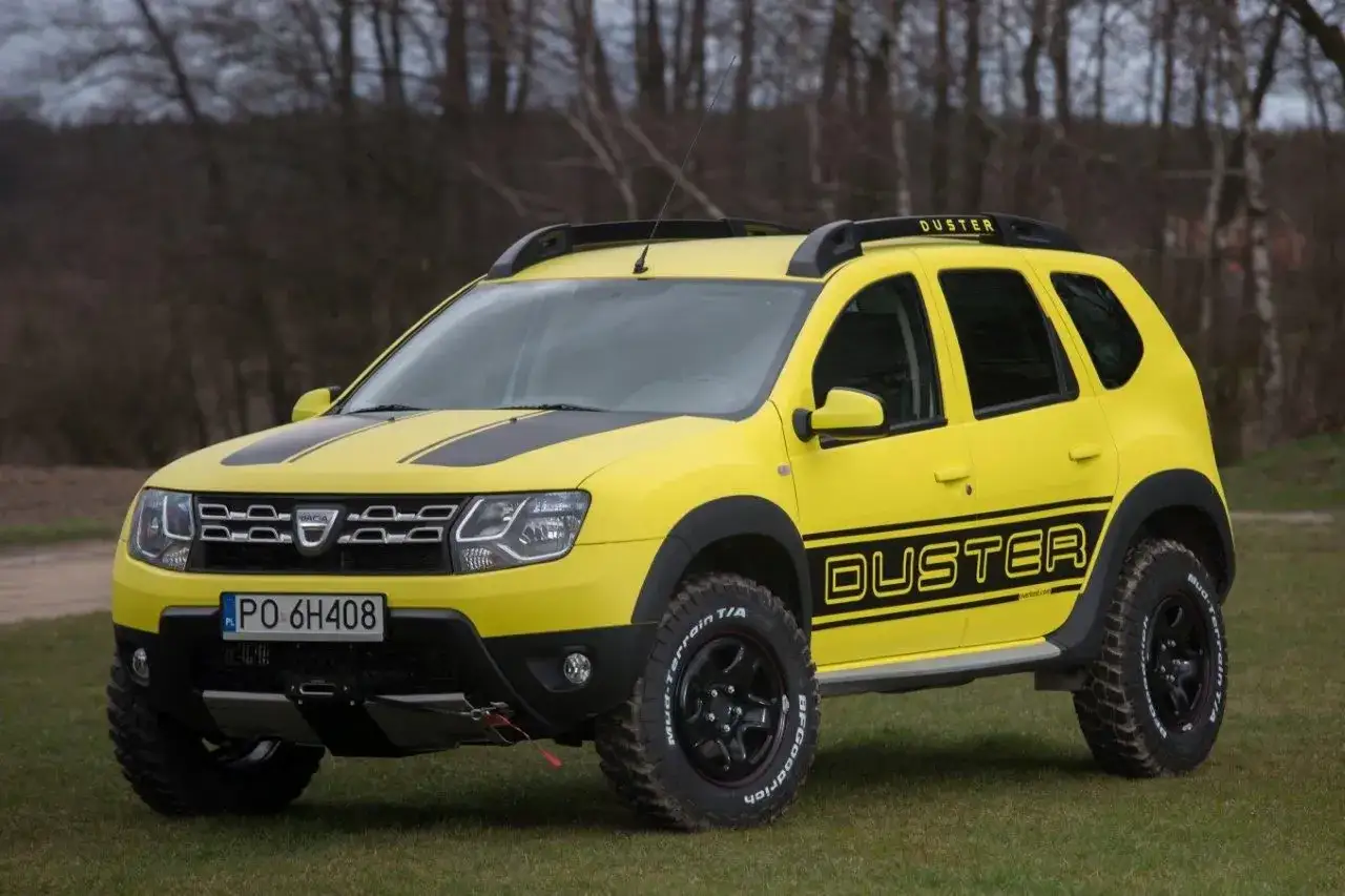Żółty Dacia Duster off road z czarnymi pasami na masce i napisem 