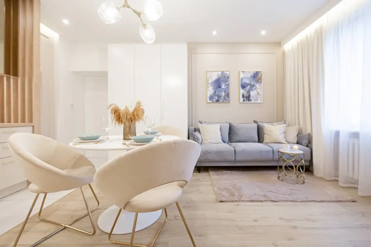 Nowoczesna jadalnia i salon z sofą, dywanem i obrazami. Wnęka na led w suficie subtelnie oświetla przestrzeń.