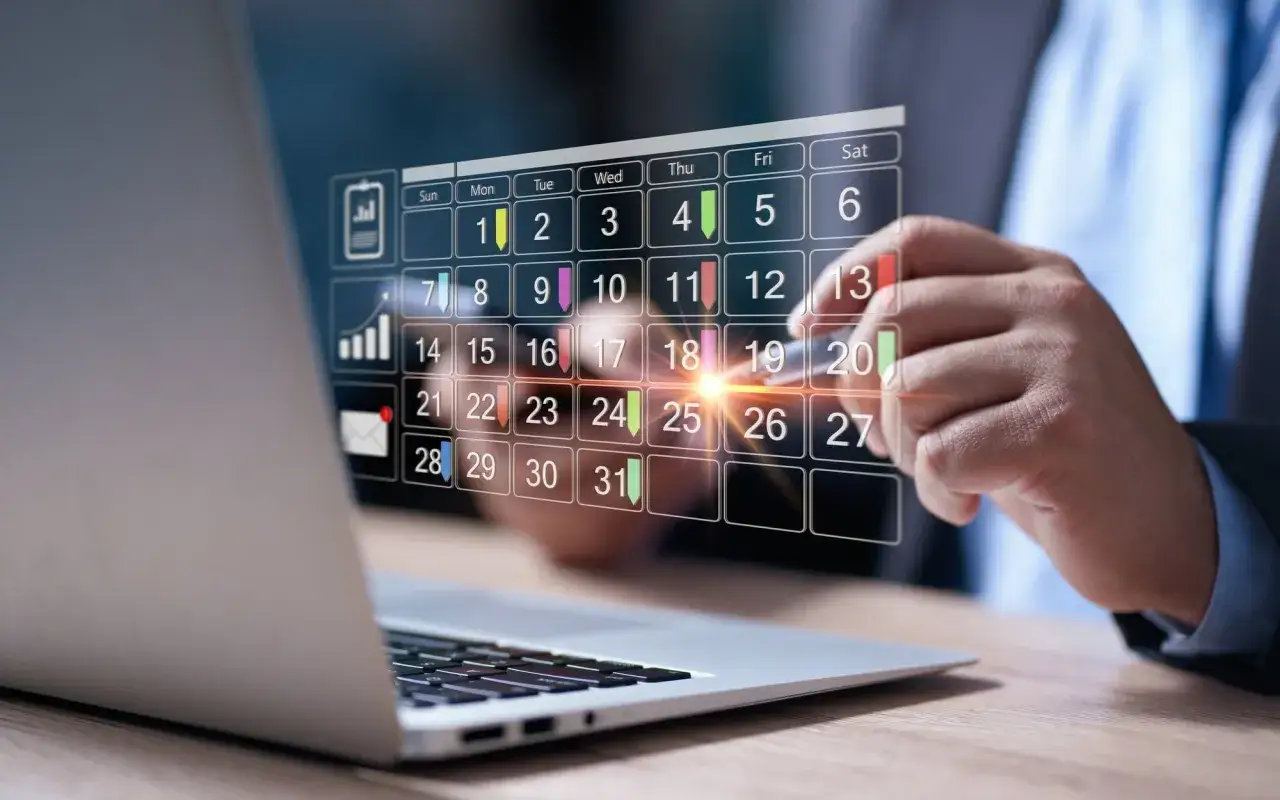 Biznesmen planuje pracę, zastanawiając się, ile to pół etatu ile to godzin tygodniowo. Kalendarz cyfrowy wyświetla dni miesiąca.