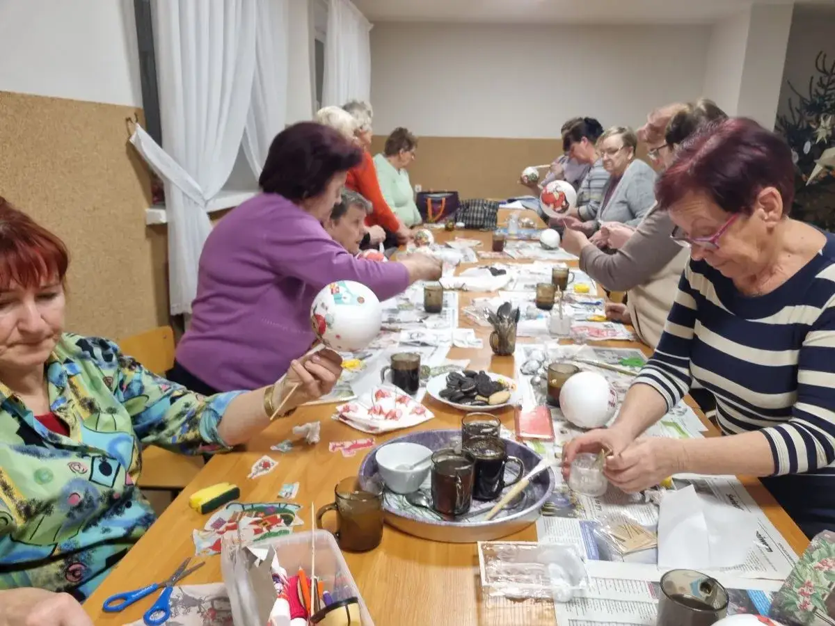 Zajęcia dla seniorów: panie ozdabiają bombki, tworząc świąteczne dekoracje.