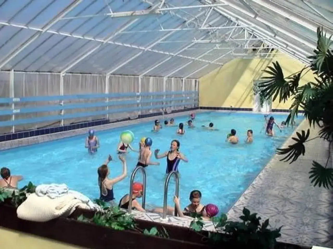 Dzieci bawią się w krytym basenie ośrodka wczasowego Janina. Radosne pluskanie i zabawy z piłkami w wodzie.