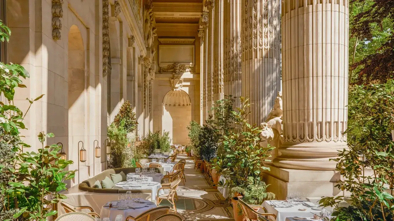 Elegancki taras restauracji w 6 dzielnicy Paryża, z rzędami kolumn i zielenią. Idealne miejsce na romantyczną kolację.