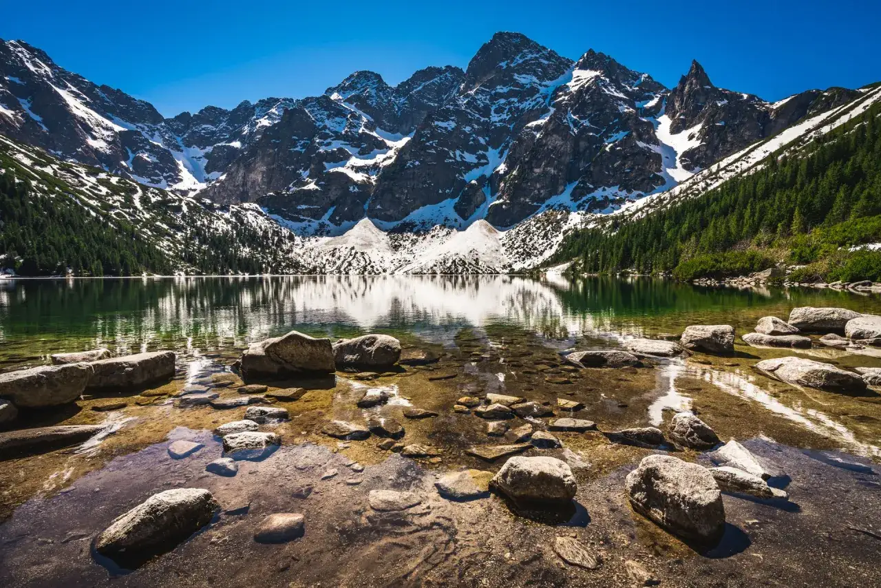Morskie Oko, idealne na najpiękniejsze trasy w Tatrach dla początkujących bez ekspozycji. Spokojna tafla jeziora odbija ośnieżone szczyty.