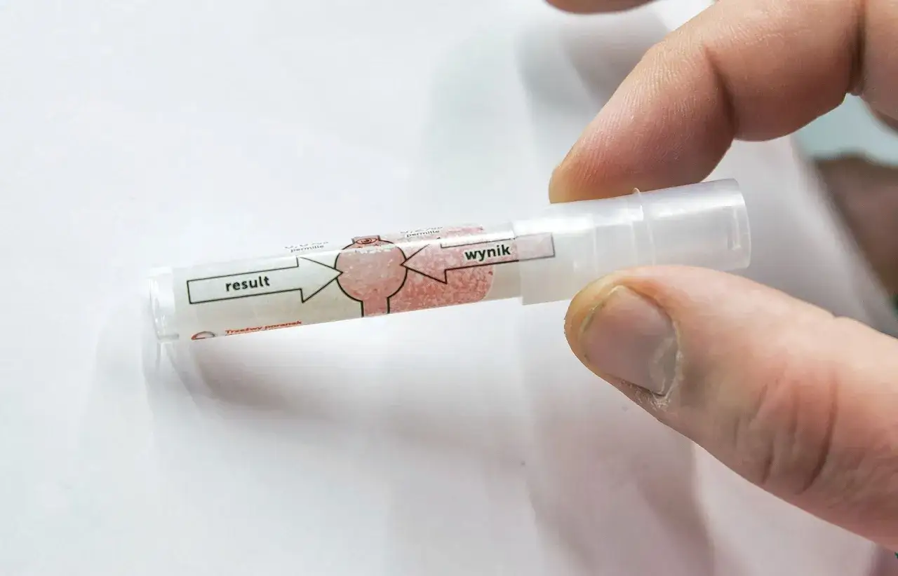 Palec trzyma jednorazowy alkomat. Czy w żabce jest alkomat? Wynik testu jest widoczny na probówce.