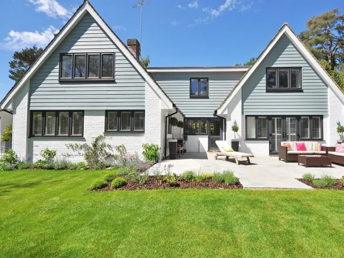 Elewacja frontowa definicja: biały dom z jasnoszarymi panelami, dużymi oknami i tarasem z meblami ogrodowymi.