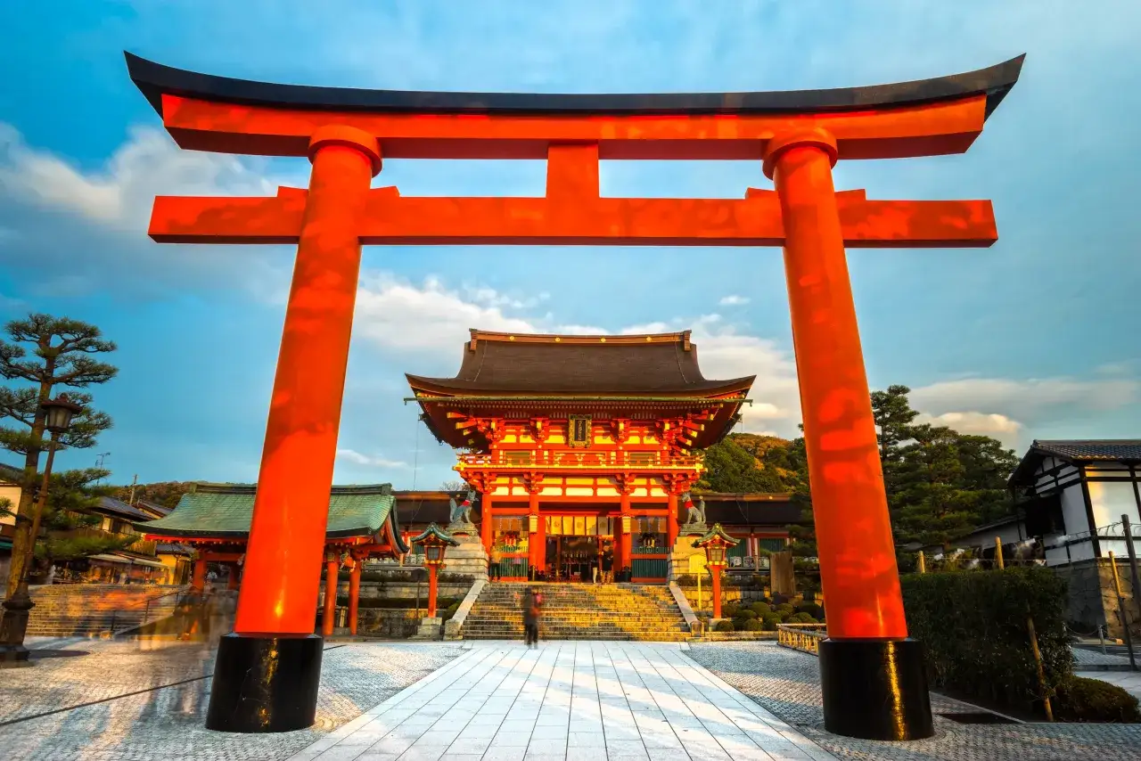 Wielka, pomarańczowa brama torii prowadzi do świątyni. To miejsce, co warto zobaczyć w Japonii, zachwyca architekturą i spokojem.