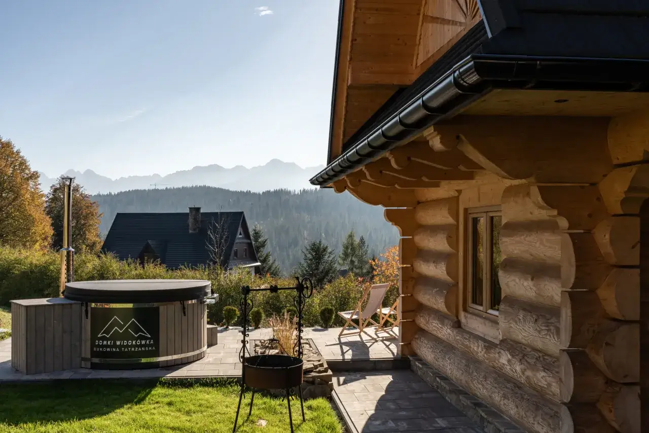 Drewniany domek z bali w Bukowinie Tatrzańskiej, z widokiem na g&oacute;ry. Obok jacuzzi i grill.