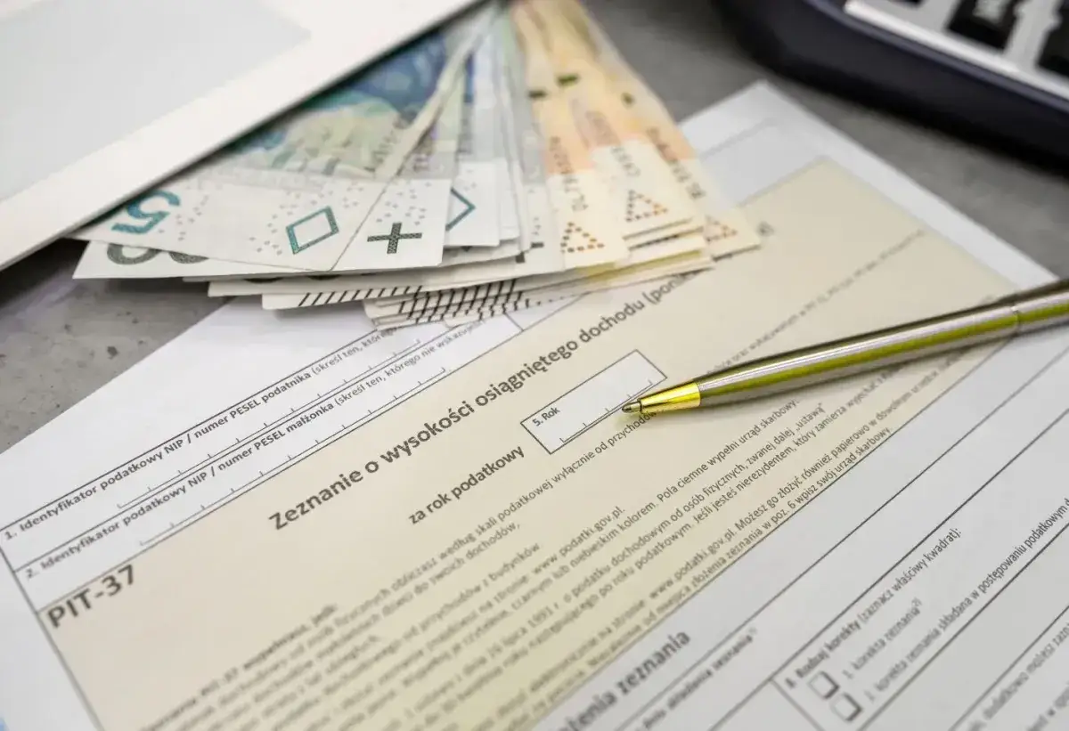 Złożenie PIT-37 z pieniędzmi na górze. Zastanawiasz się, ile można zarobić bez podatku? Długopis czeka na wypełnienie zeznania.
