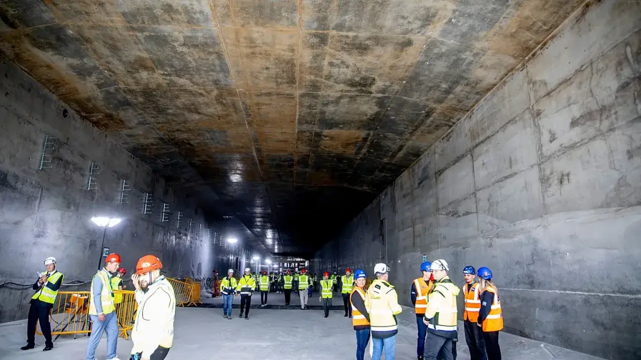 Grupa ludzi w kaskach zwiedza ogromny, betonowy tunel. To przyszła trasa kolejowa łącząca Niemcy i Danię.